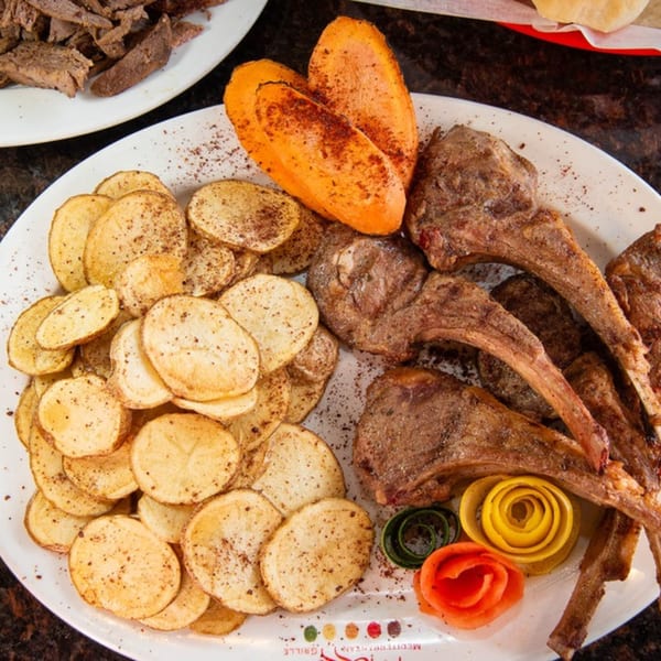 Mezza Mediterranean Grille's lamb chops with roasted potatoes, carrots, and decorative vegetable garnishes.